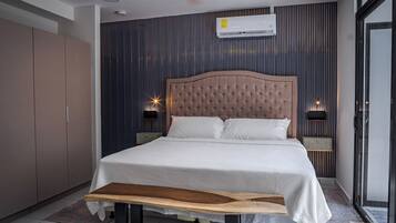 Een moderne slaapkamer met een gestapeld hoofdeinde, een houten bankje en een grote garderobe.