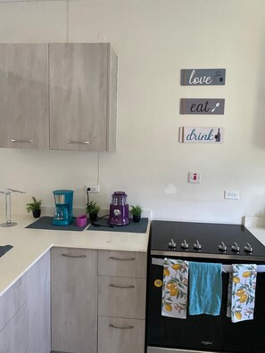 A kitchen with light wooden cabinets, a black stove, and a coffee maker on the counter. - Beautiful 2-bedroom house with AC in Discovery Bay (Discovery Bay)