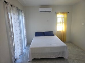A single bed with a white mattress and blue pillows in a room with a tiled floor. - Beautiful 2-bedroom house with AC in Discovery Bay (Discovery Bay)