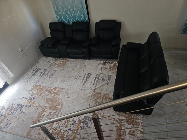 A room with a patterned floor, a metal railing, and two rows of black chairs. - Beautiful 2-bedroom house with AC in Discovery Bay (Discovery Bay)