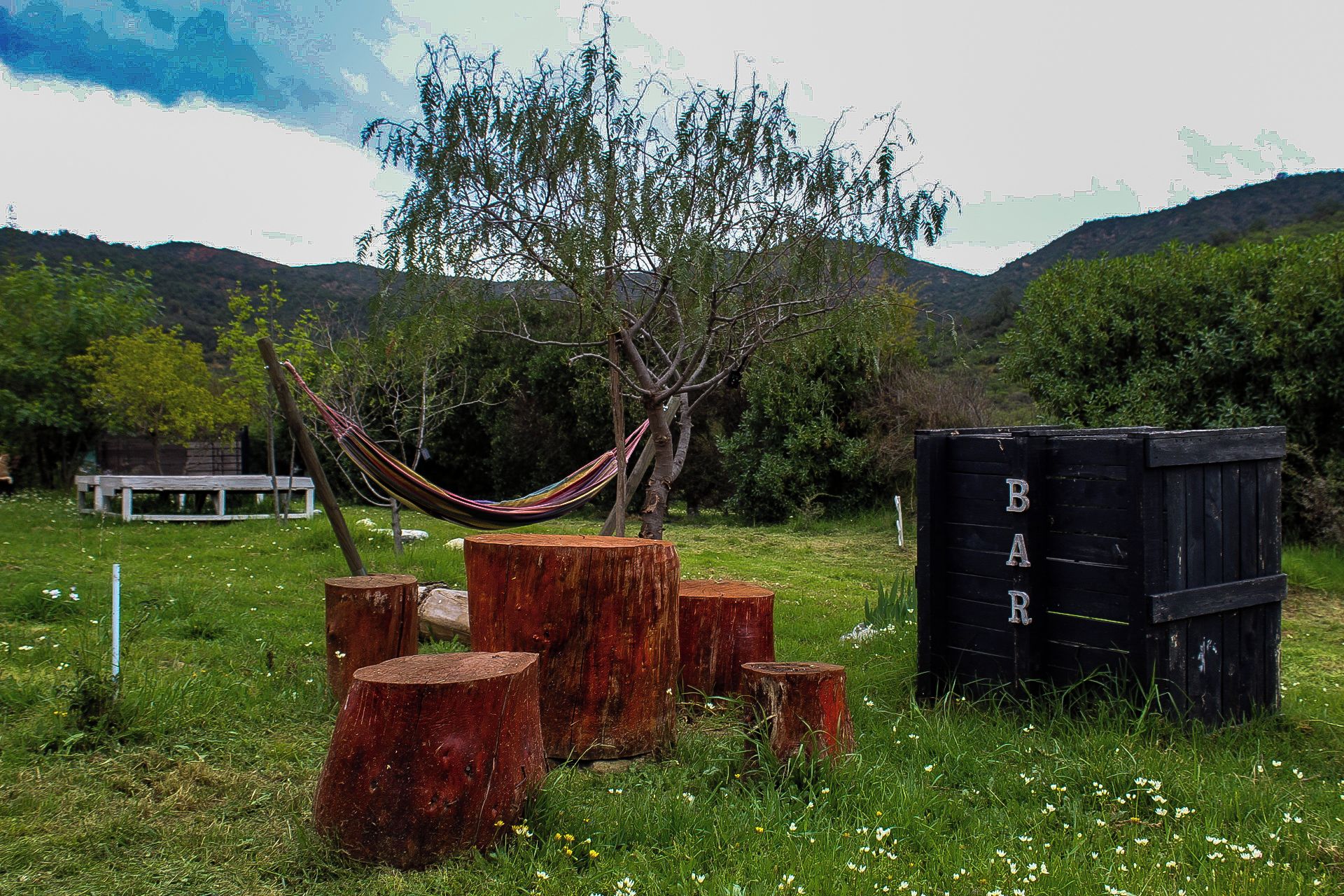 Una hamaca, tocones de madera y una estructura negra con letras.