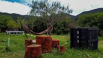 Una hamaca, tocones de madera y una estructura negra con letras.