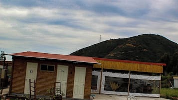 A wooden cabin with a red roof, a covered outdoor area, and a swimming pool.
