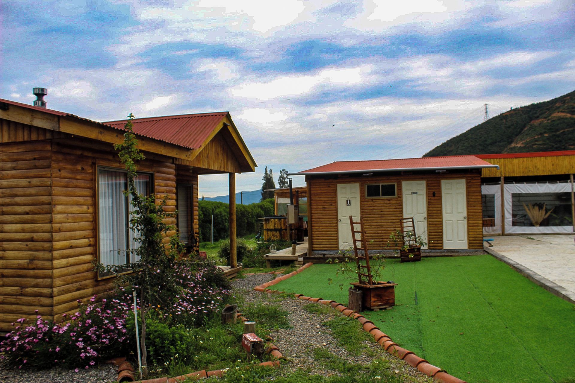 A wooden cabin with a porch, a small garden with flowers, and a clear sky.