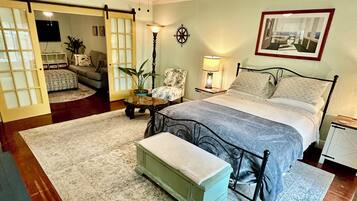A bedroom with a bed, bedside tables, a ceiling fan, a wall-mounted lamp, and a framed picture.