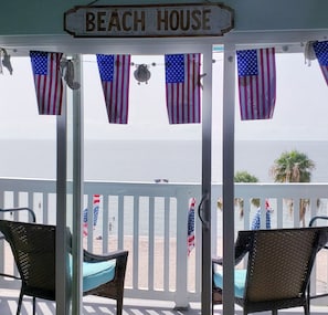 A beach house with a porch, American flags, and a view of the beach. - END Condo directly on the Beach with unobstructed views of the ocean (Corpus Christi)