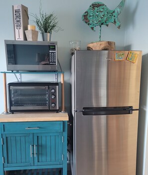 A kitchen with a stainless steel refrigerator, a microwave, and a toaster oven on a teal cabinet. - END Condo directly on the Beach with unobstructed views of the ocean (Corpus Christi)