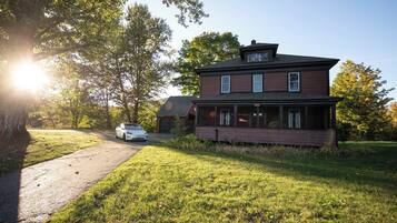 A two-story house with a porch, a driveway, and a car parked in front.