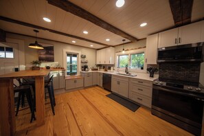 Una cocina moderna con suelo de madera, armarios blancos, una isla central y electrodomésticos integrados.