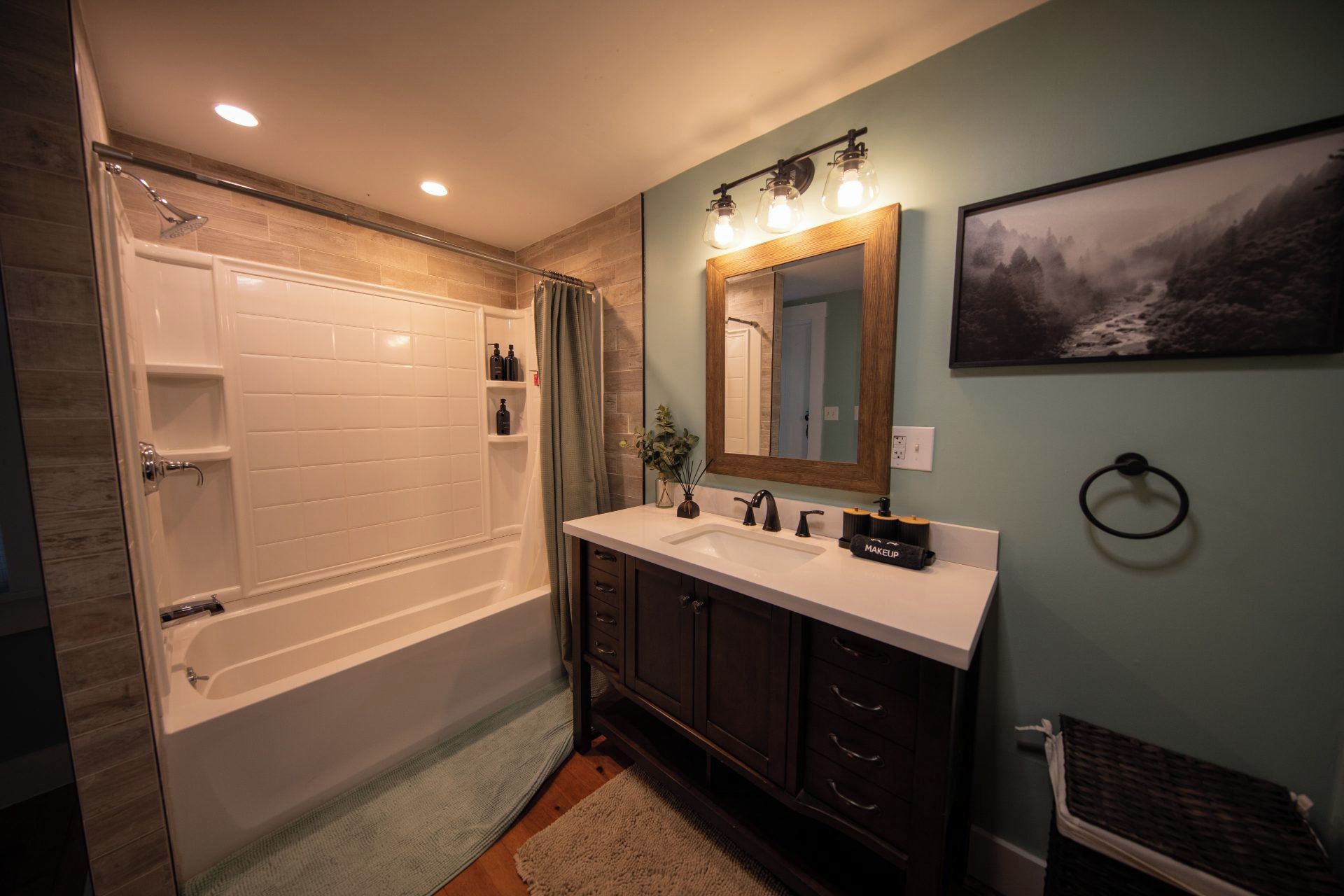 A bathroom with a bathtub, a vanity with a mirror, and a framed picture on the wall.