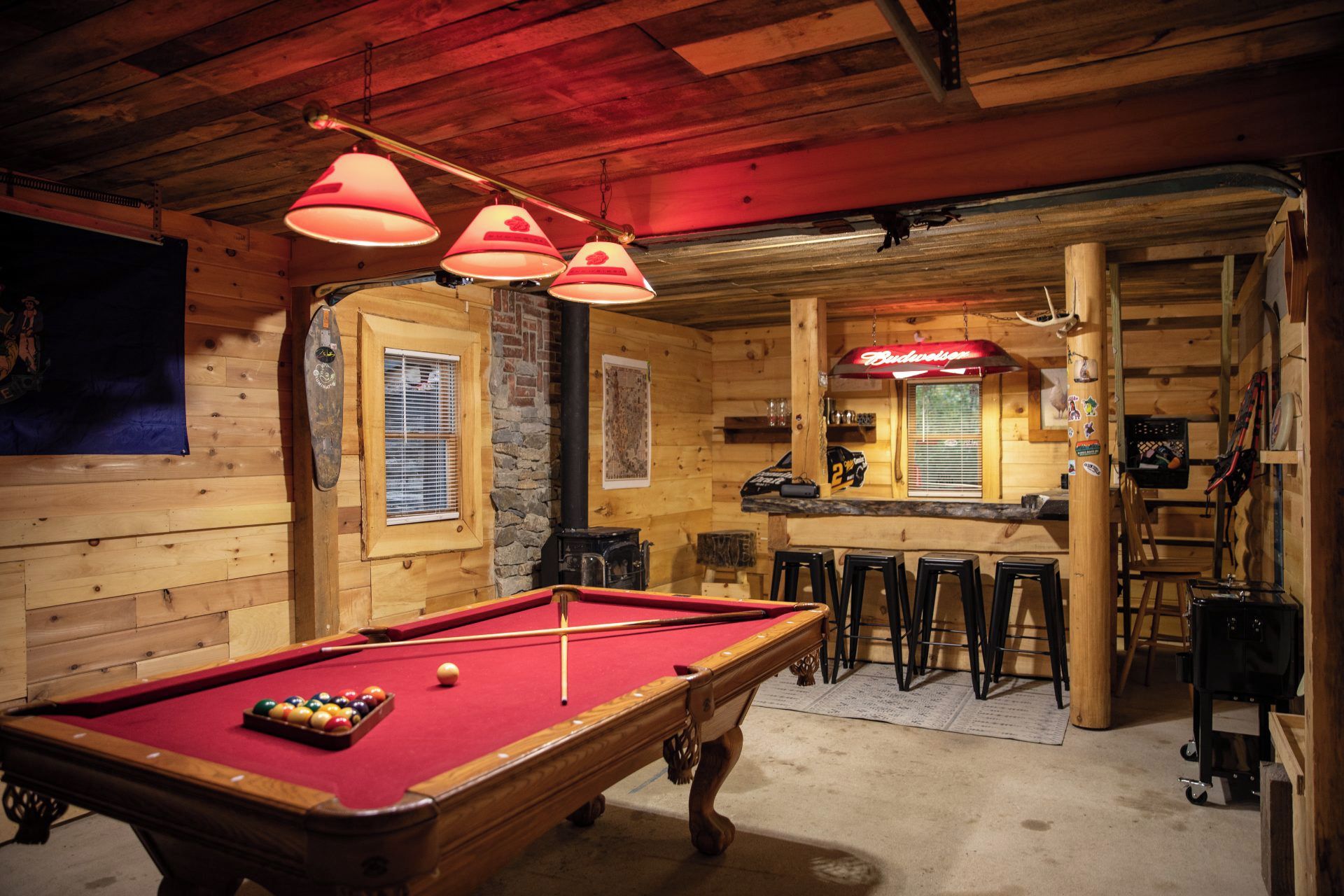 A pool table with balls, a bar area with stools, and a wooden interior.
