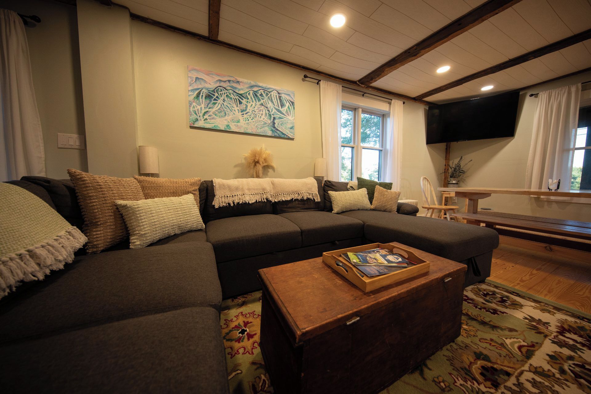 A living room with a sectional sofa, a wooden coffee table, and a painting on the wall.