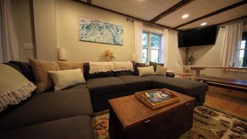 A living room with a sectional sofa, a wooden coffee table, and a painting on the wall.