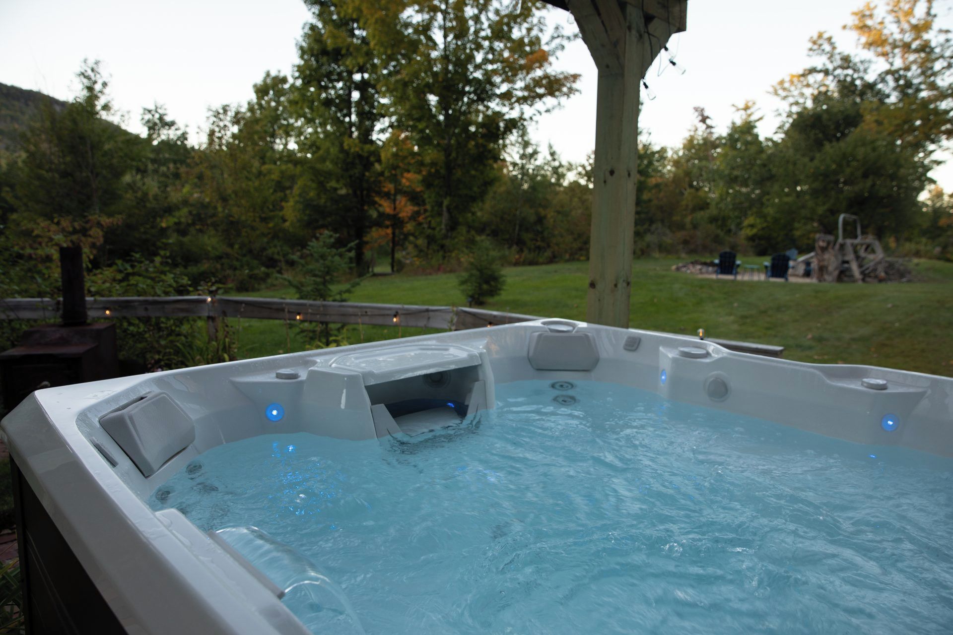 A hot tub with a wooden deck and a tree in the background.