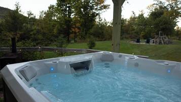 A hot tub with a wooden deck and a tree in the background.