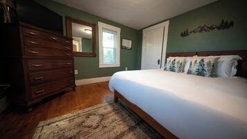 A bedroom with a bed, dresser, and a window.