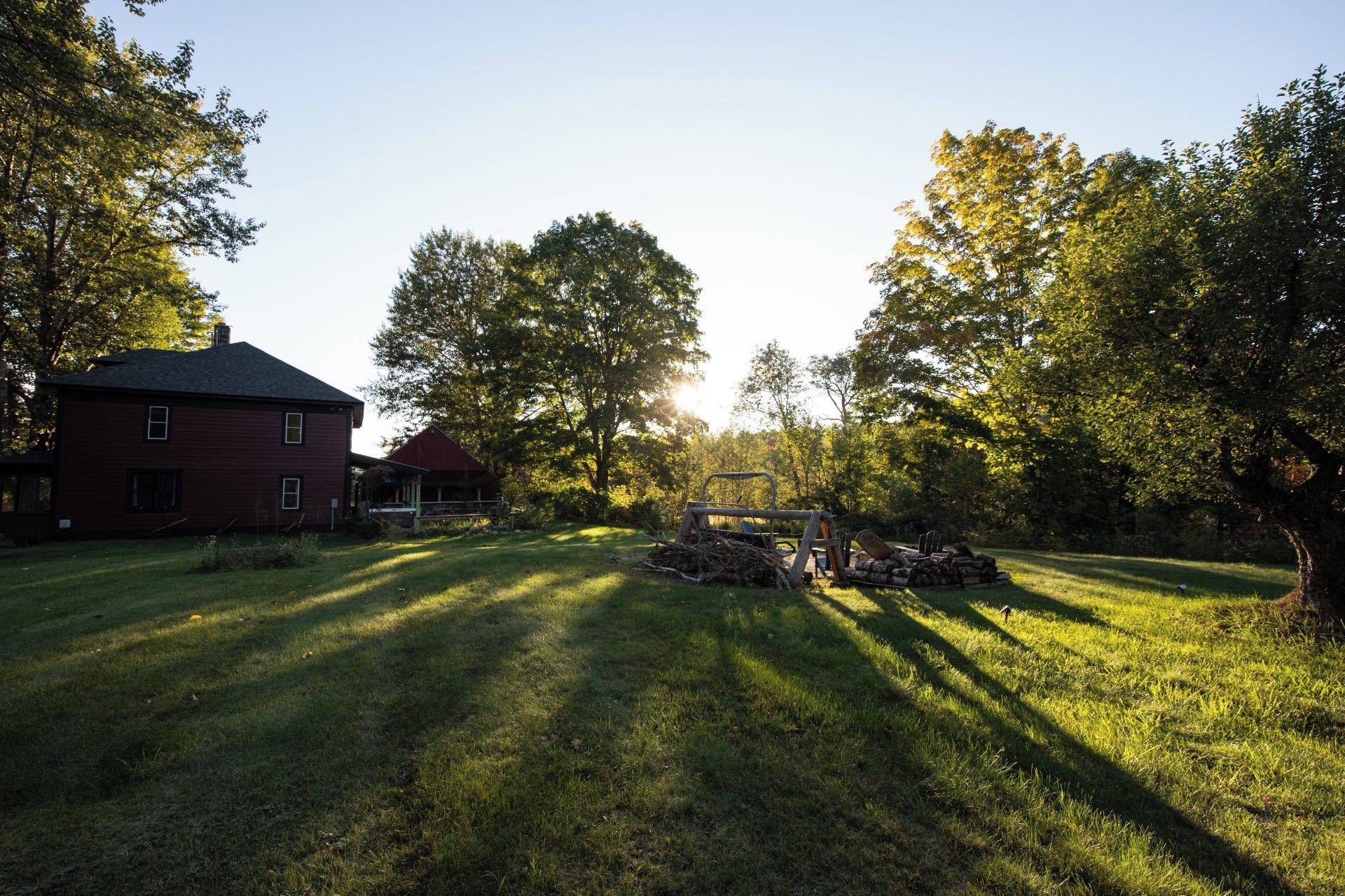 A red building with a porch, surrounded by a grassy yard and trees.