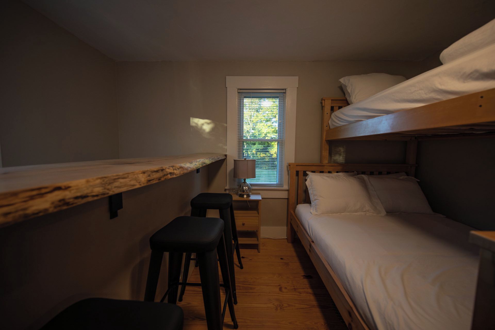 A compact room with bunk beds, a small desk, and a window.