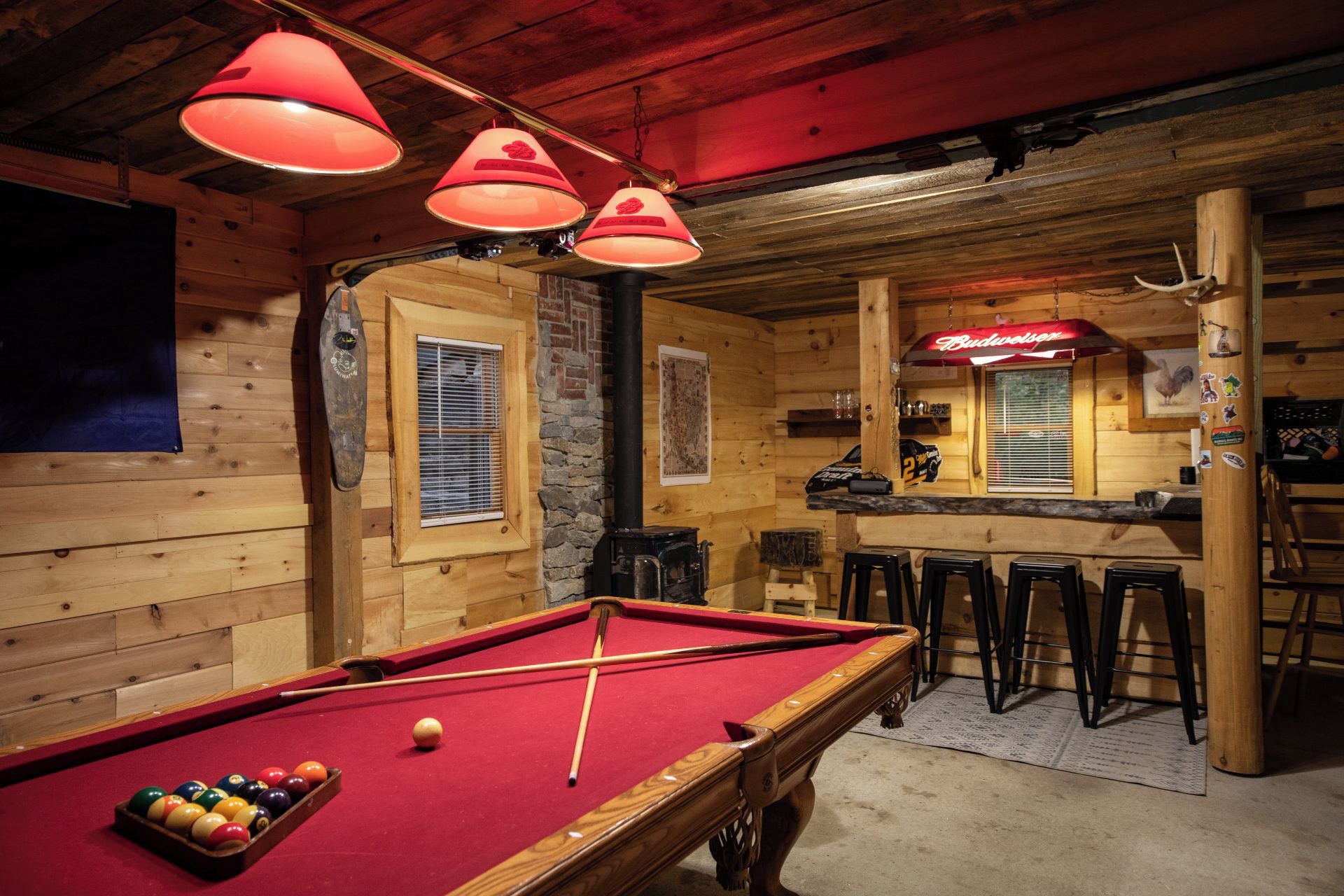 Une table de billard avec des billes, un bar avec des tabourets et un décor intérieur en bois.