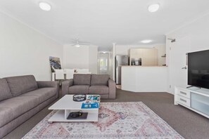 A modern living room with a sofa, coffee table, and a television. - Miami Resort Living - Two Bedroom Resort Views (Gold Coast)
