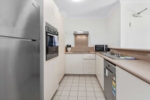 A compact kitchen with a stainless steel refrigerator, oven, microwave, and dishwasher. - Miami Resort Living - Two Bedroom Resort Views (Gold Coast)