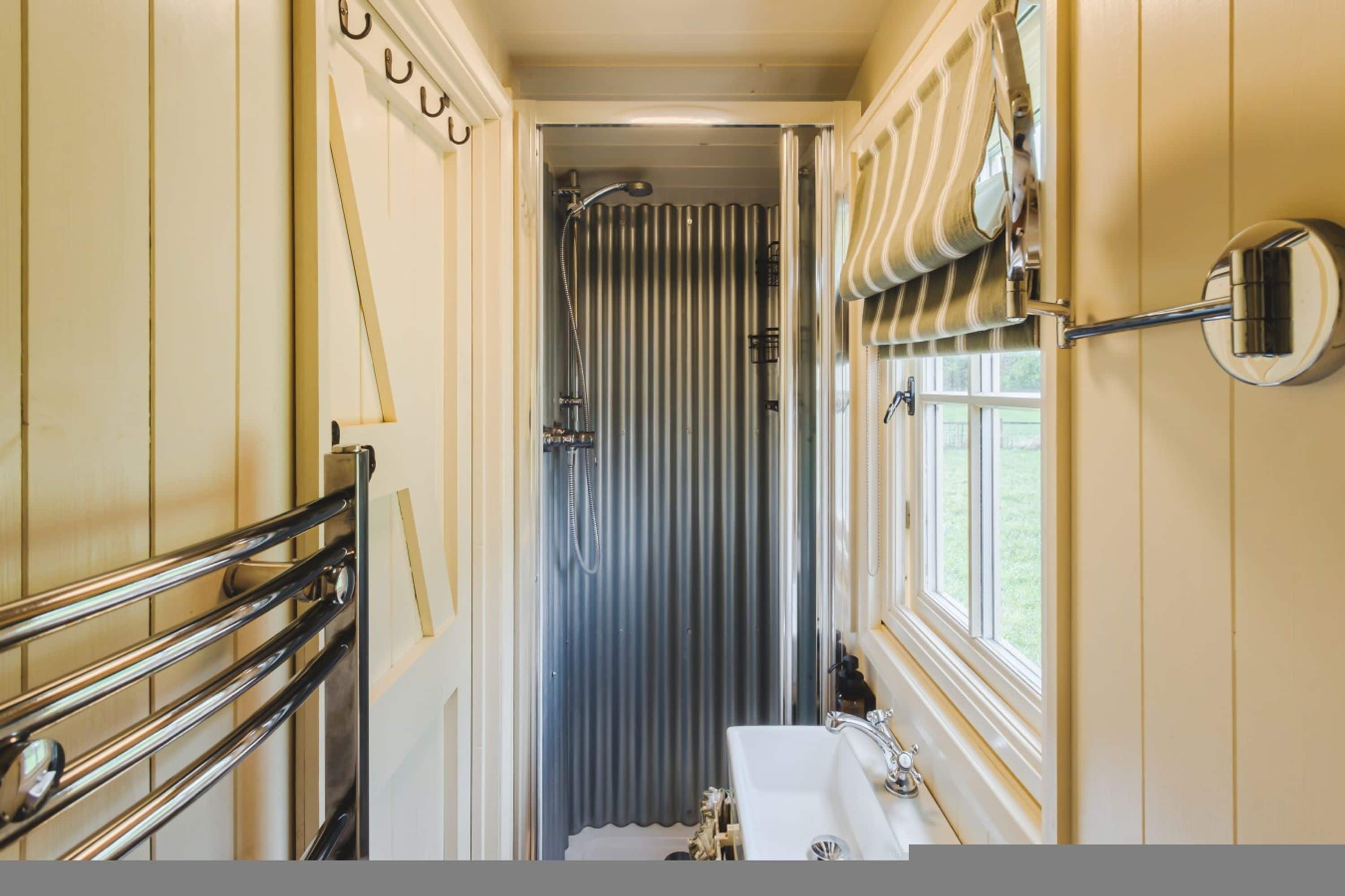 A narrow bathroom with a shower, a toilet, and a sink.