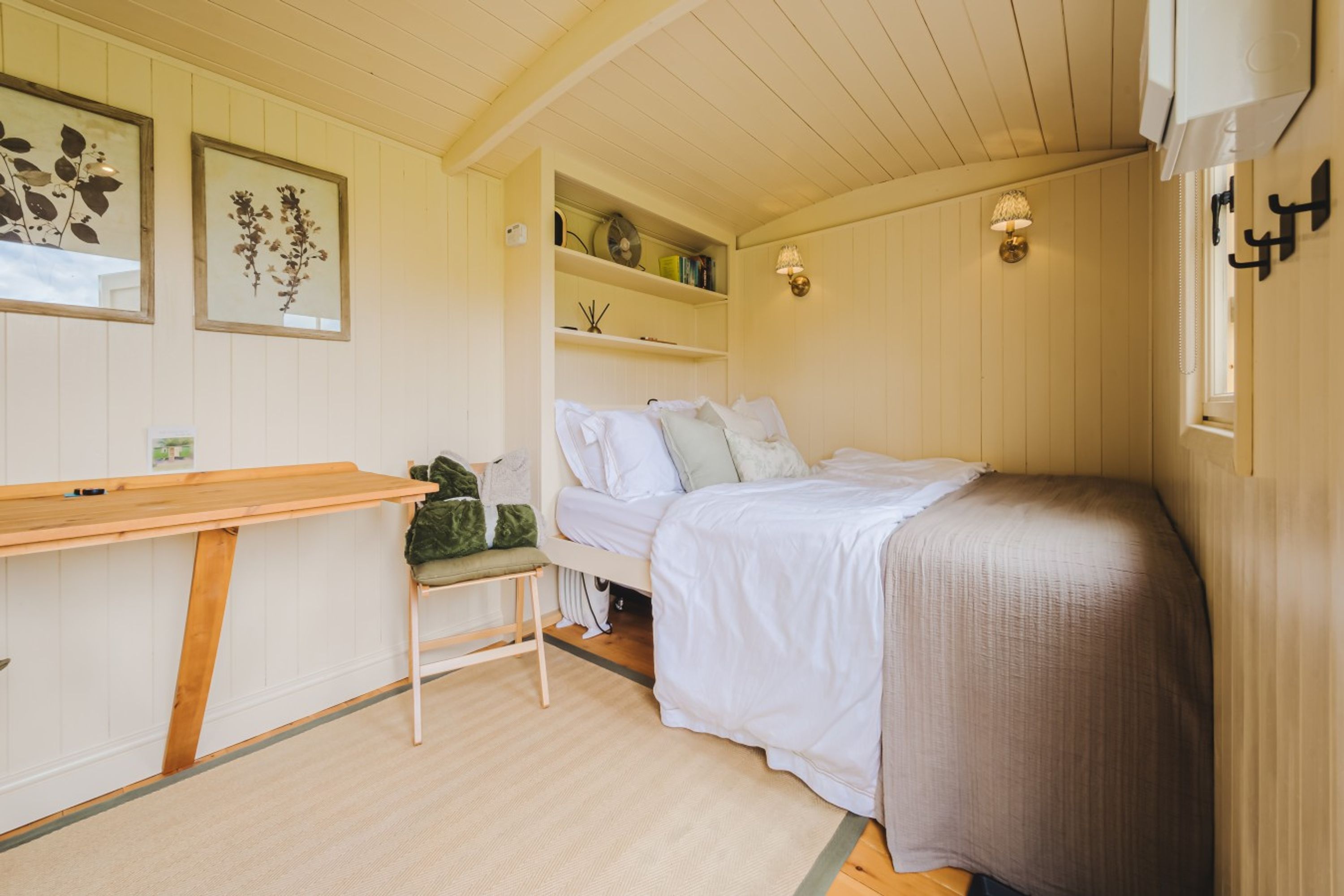 Un dormitorio acogedor con una cama, un escritorio pequeño y estanterías con libros y objetos decorativos.