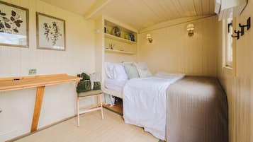 Un dormitorio acogedor con una cama, un escritorio pequeño y estanterías con libros y objetos decorativos.
