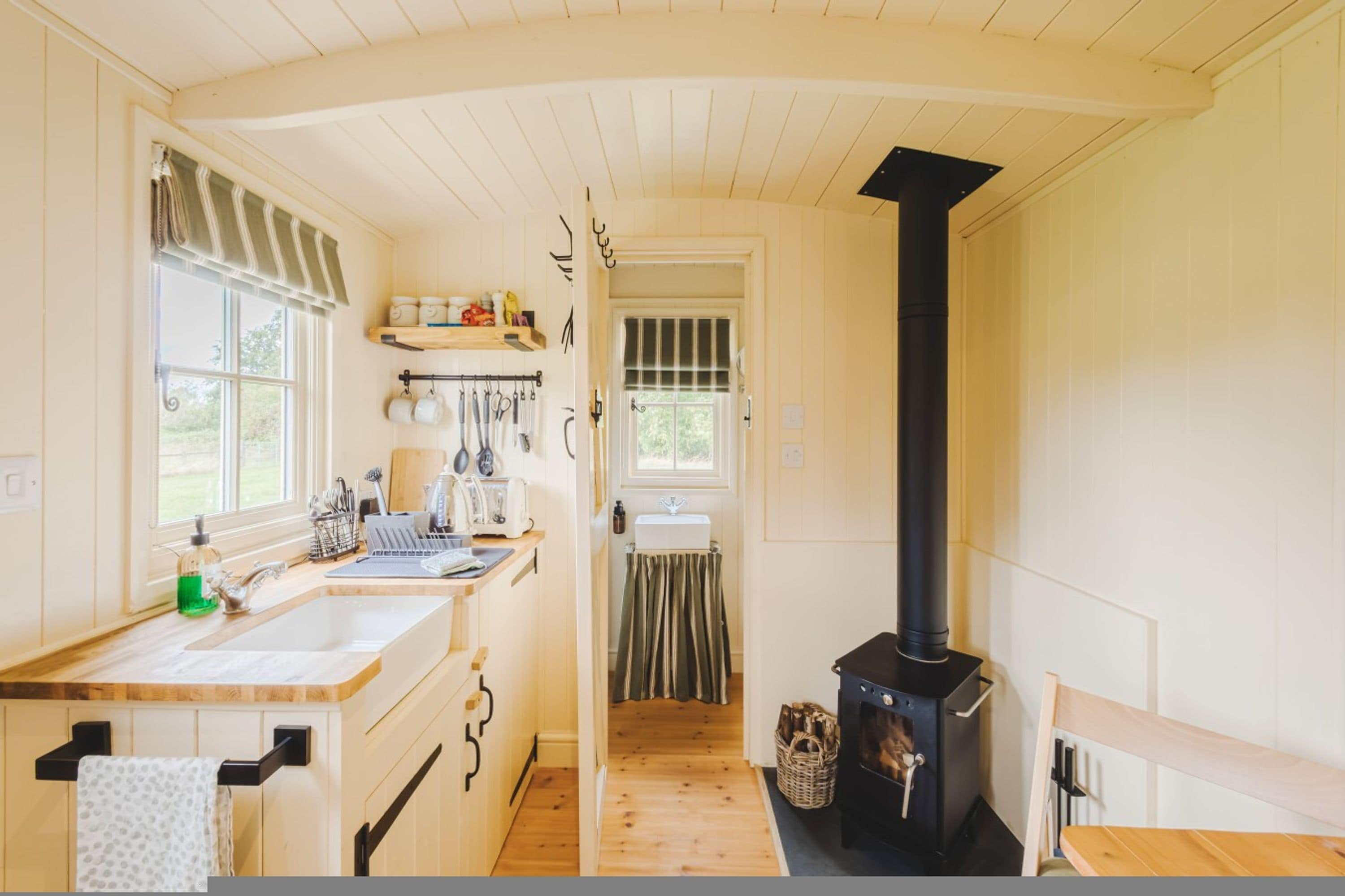 A kitchen with wooden cabinets, a sink, a stove, and a window with curtains.