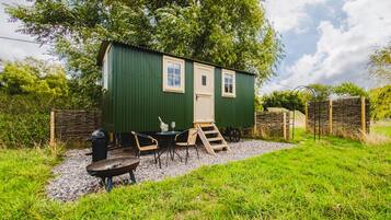 Una cabaña de madera verde con un porche pequeño, una ventana y una puerta.