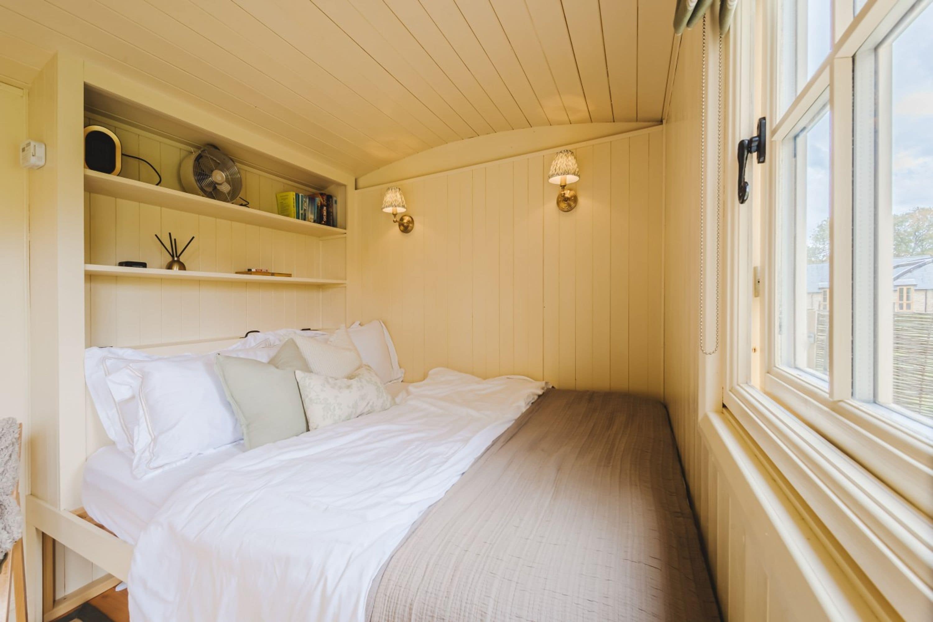 Ein Schlafzimmer mit einem Bett, Regalen und zwei Wandlampen.