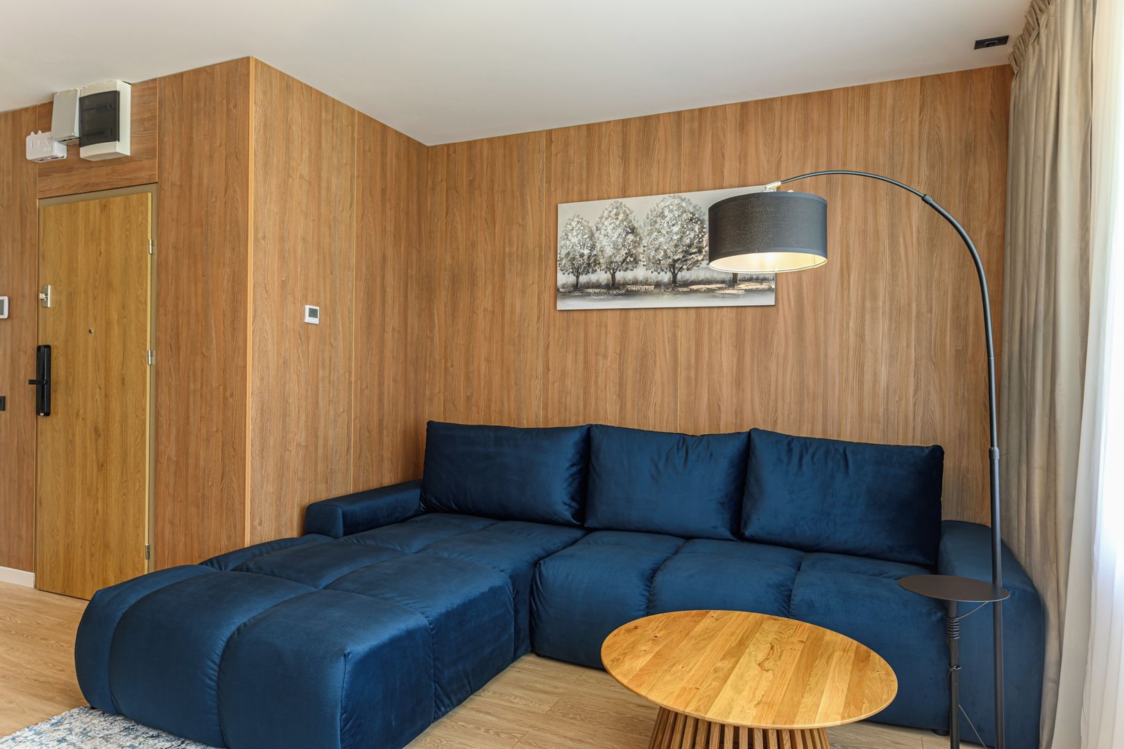 A modern living room with a sectional sofa, a round wooden coffee table, and a floor lamp.