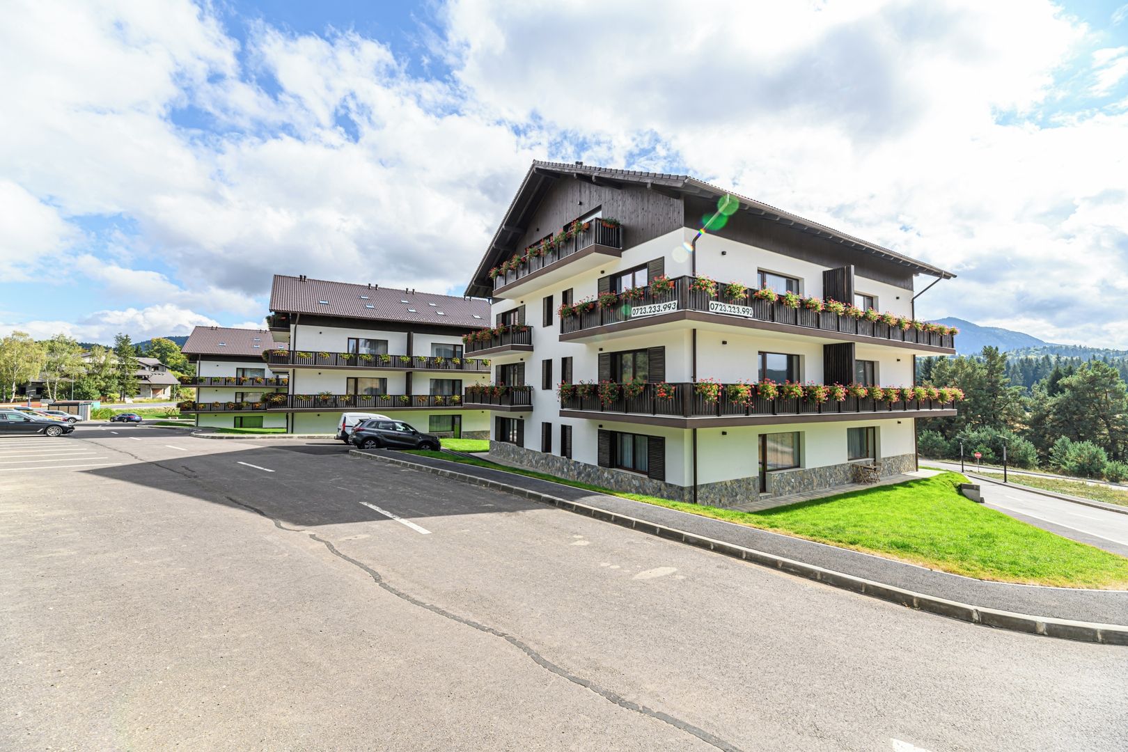 Hotel de vários andares com varandas, estacionamento e vista para a paisagem ao redor.