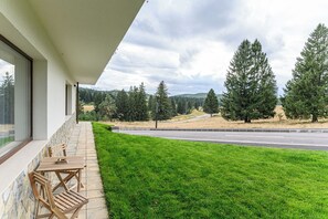 Un espace extérieur aménagé de façon moderne, avec des sièges et une vue sur une route et des arbres.