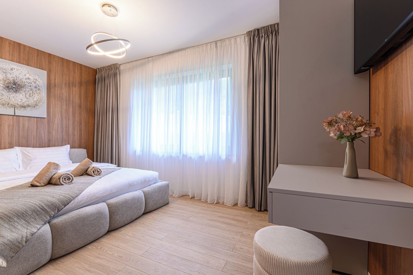 A modern bedroom with a bed, a bedside table, a chair, and a TV.