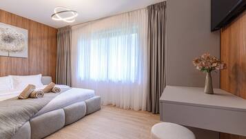 A modern bedroom with a bed, a bedside table, a chair, and a TV.