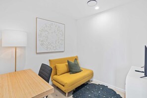 A modern living room with a yellow sofa, a black chair, a wooden table, a floor lamp, and a black rug. - Luxury Ocean View Burleigh Apartment (Gold Coast)
