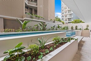 Ein moderner Poolbereich im Freien mit abgestuften Pflanzkübeln und einem klaren, blauen Pool.