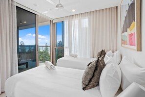 Une chambre d’hôtel avec deux lits, une grande fenêtre avec des rideaux, un ventilateur de plafond et une vue sur l’extérieur.