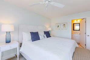 Ein Schlafzimmer mit einem Bett, zwei Nachttischen mit Lampen, einem Deckenventilator und einer Tür zu einem Badezimmer.