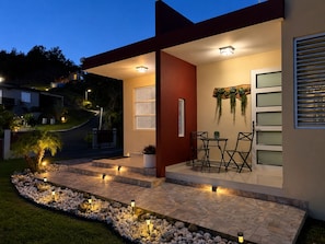 A modern house with a covered patio, outdoor seating, and a landscaped garden.