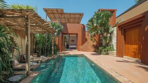 A pool area with a clear blue pool, a wooden pergola, and a staircase leading to a room. - Villa NAVAHO (Badung)