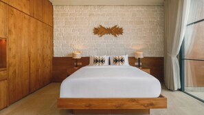 A bedroom with a wooden bed, a stone wall, and a large window with curtains. - Villa NAVAHO (Badung)