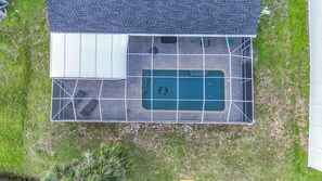 Eine Luftaufnahme eines Hauses mit Swimmingpool, überdachter Terrasse und umzäunter Garten.