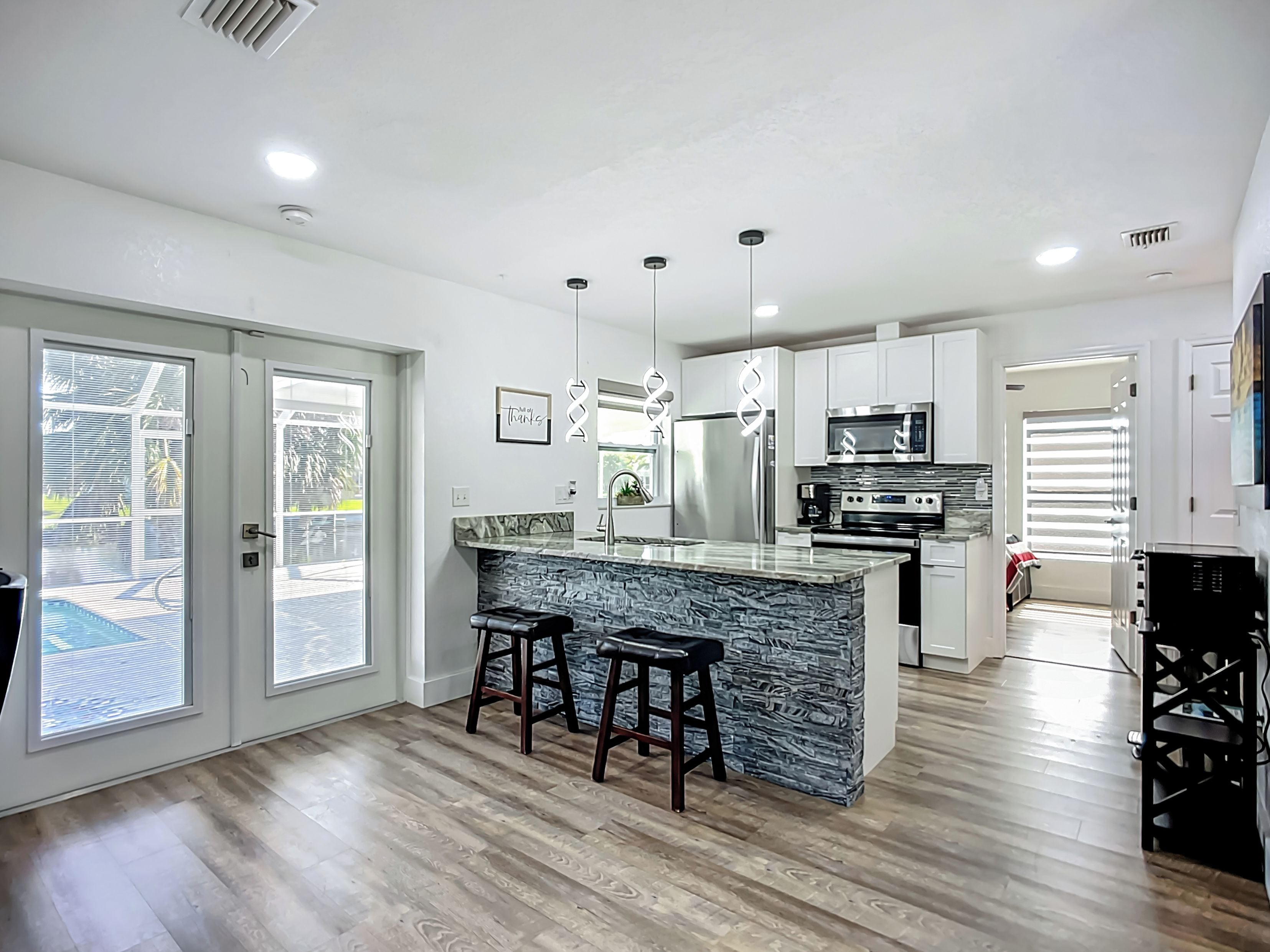 A modern kitchen with a central island, stainless steel appliances, and a view to the outside.