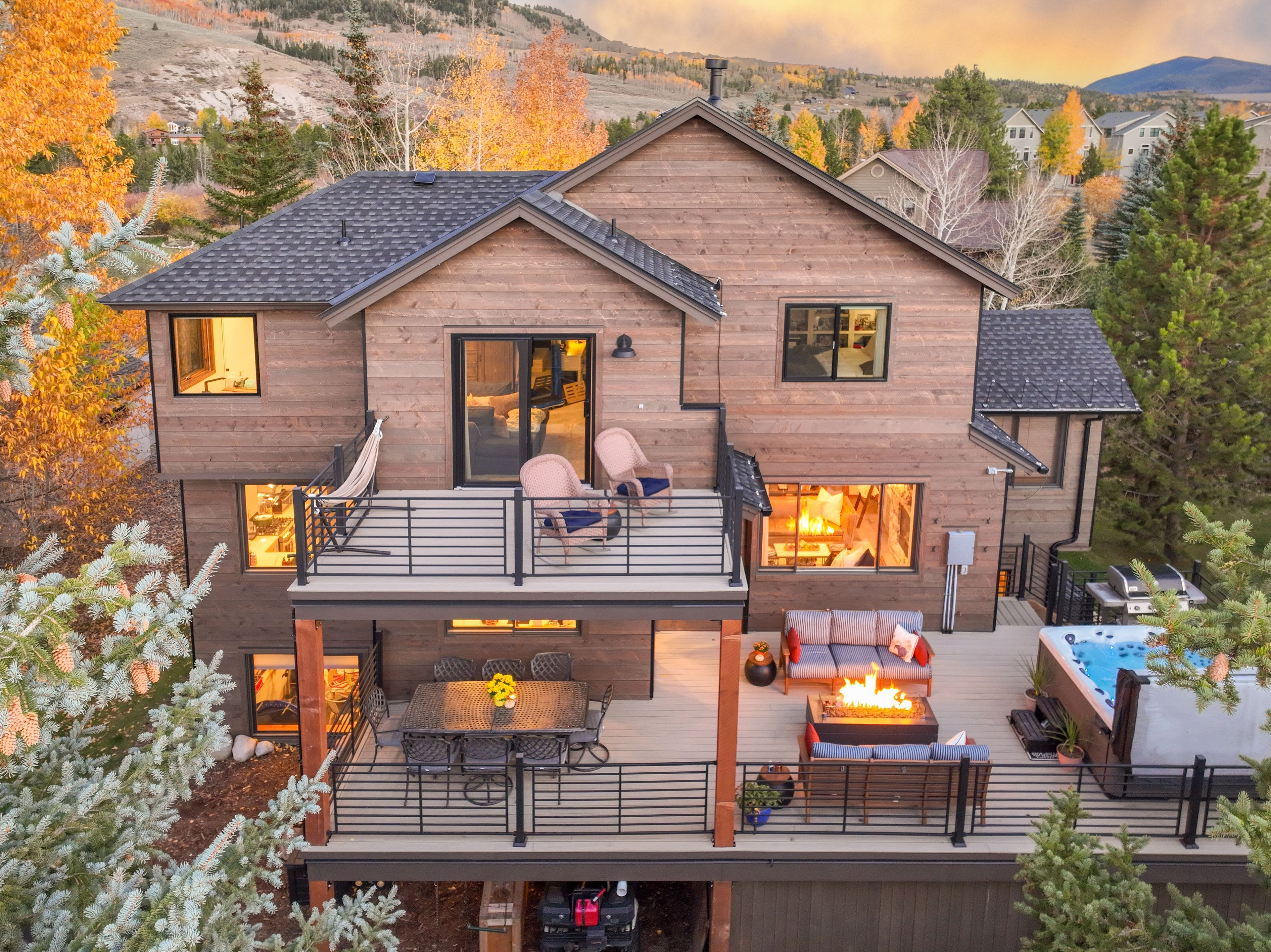 Une maison en bois à deux étages, dotée d’un balcon, d’un jacuzzi et d’une cheminée.