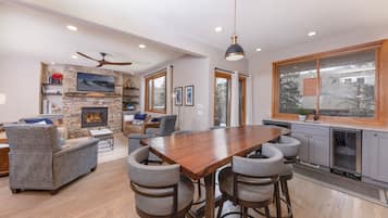 A modern kitchen with a wooden table, bar stools, and a built-in oven.