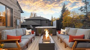 An outdoor deck with a fire feature, two sofas, and a hot tub.