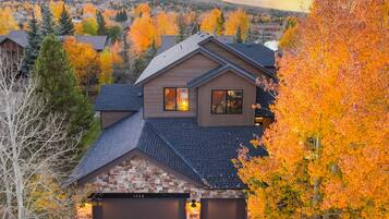 A two-story house with a stone foundation, a garage, and a view of a mountainous landscape.