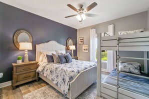 A bedroom with a bed, a nightstand, a dresser, a ceiling fan, and a bunk bed. - Ocean View | Inflatable Hot Tub | Arcade Game (Crystal Beach)